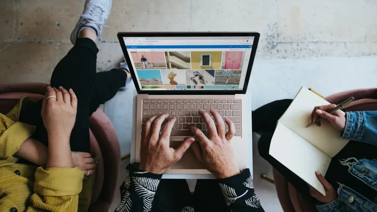 Zespół marketingu realizuje zadania: jedna osoba pisze na laptopie, druga notuje w zeszycie.