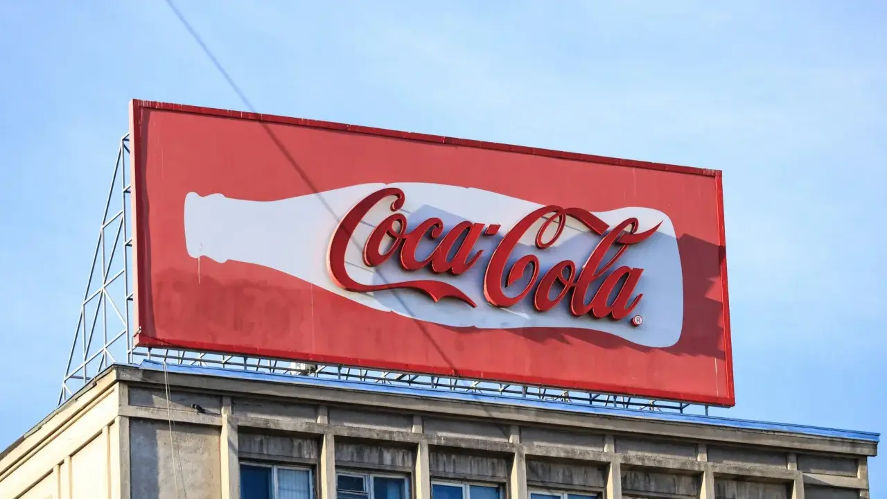 Reklama Coca-Coli, jeden z najbardziej słynnych haseł reklamowych, na tle błękitnego nieba.