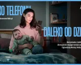 Matka z dzieckiem w reklamie. Kobieta patrzy w telefon, dziecko obok. Przesłanie: ograniczaj ekrany, gdy jesteś z dzieckiem.