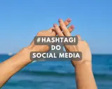 Dwie dłonie tworzą znak #. Tekst: #HASHTAGI DO SOCIAL MEDIA. Idealne gotowe hashtagi na wakacje.