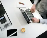 Biurko z laptopem, kawą i telefonem Cisco. Czy to jest CPL? Tak, to miejsce pracy.