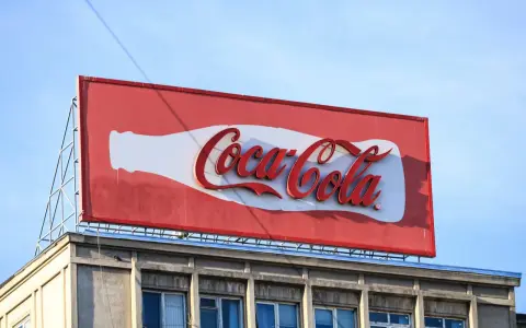 Reklama Coca-Coli, jeden z najbardziej słynnych haseł reklamowych, na tle błękitnego nieba.