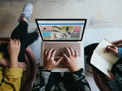 Zespół marketingu realizuje zadania: jedna osoba pisze na laptopie, druga notuje w zeszycie.