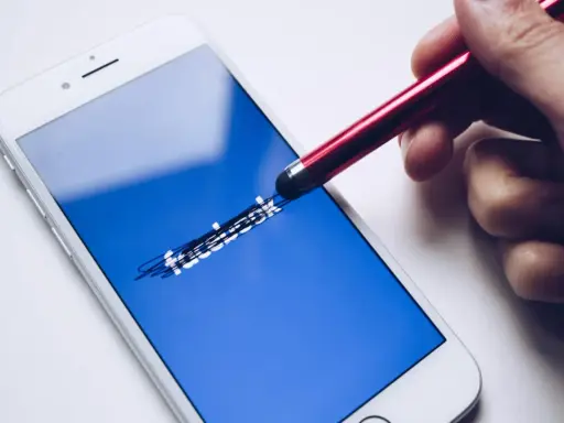 Dłoń z rysikiem próbuje odblokować dezaktywowane konto na FB.