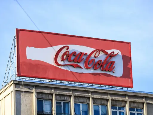 Reklama Coca-Coli, jeden z najbardziej słynnych haseł reklamowych, na tle błękitnego nieba.