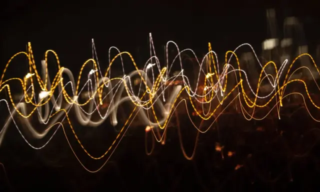 Dynamiczna reklama w postaci falujących linii świetlnych, przypominających ruch uliczny nocą.